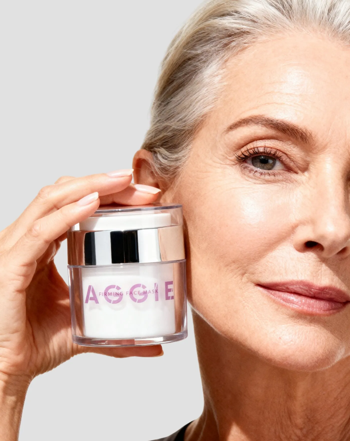 Kobieta 50+ trzyma maskę liftingującą Aggie przy twarzy